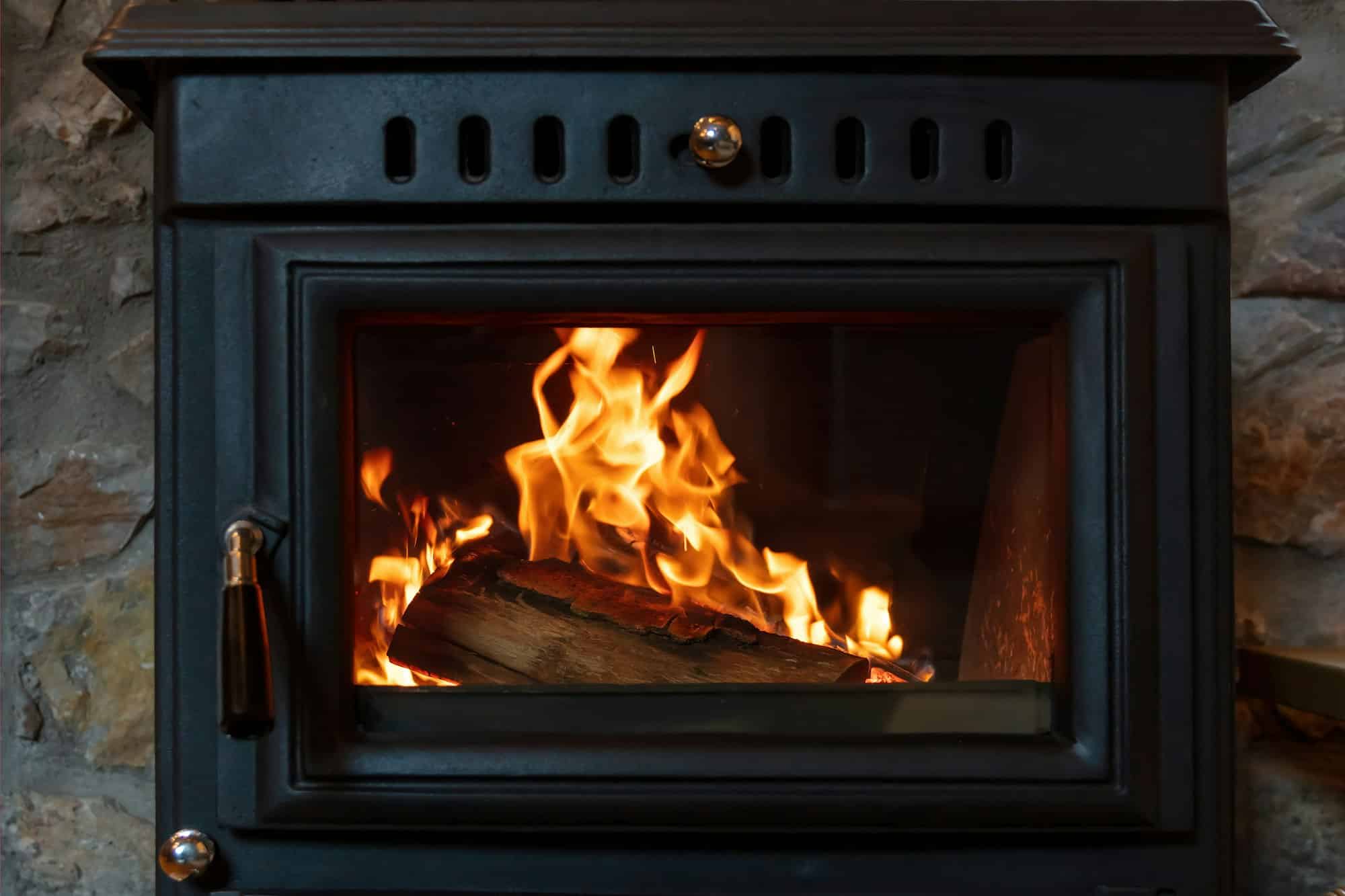 Burning fire in a wood stove fireplace radiates heat, warm home interior,