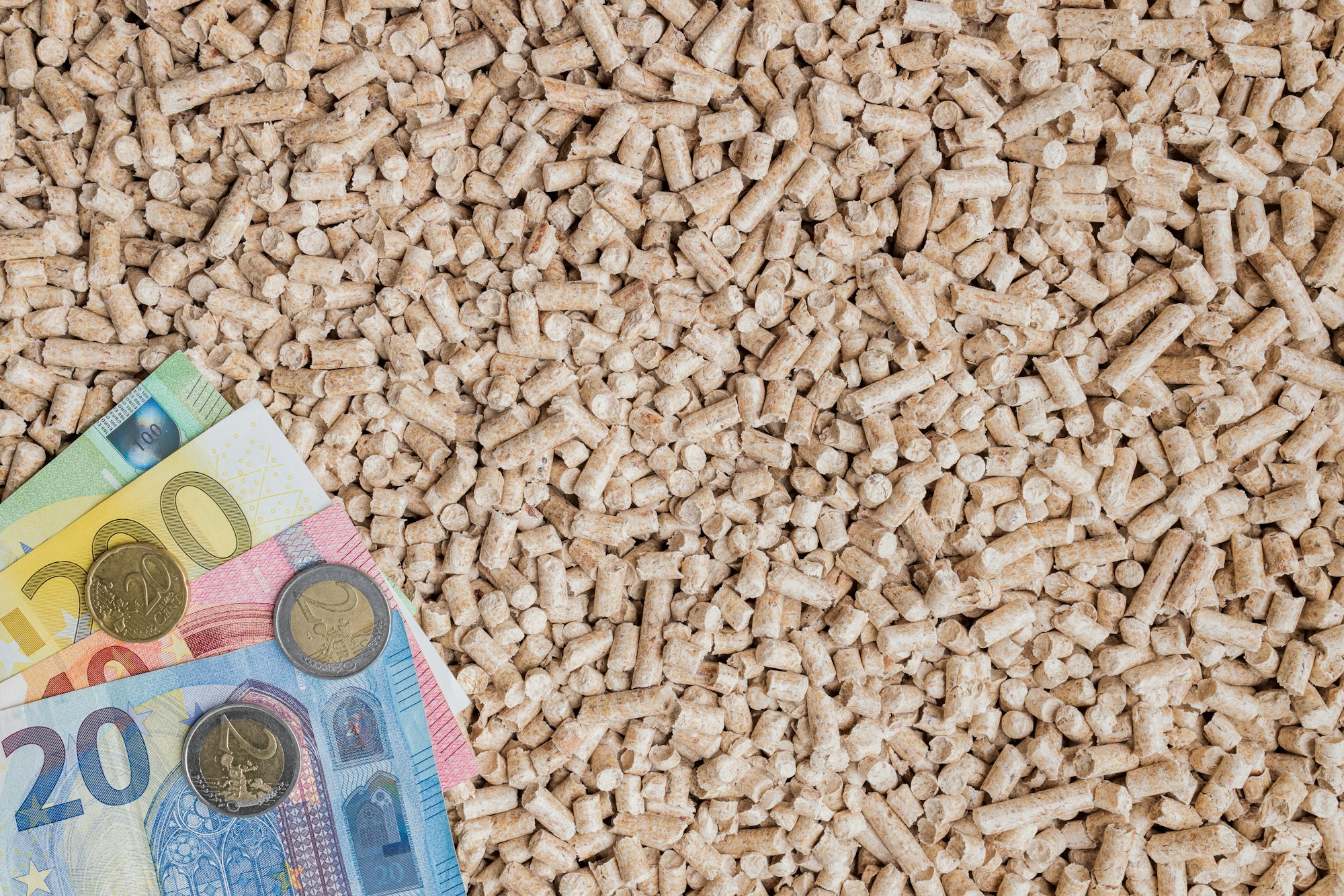 Wooden pellets background with euro banknotes. Biofuel, ecological heating, alternative energy.