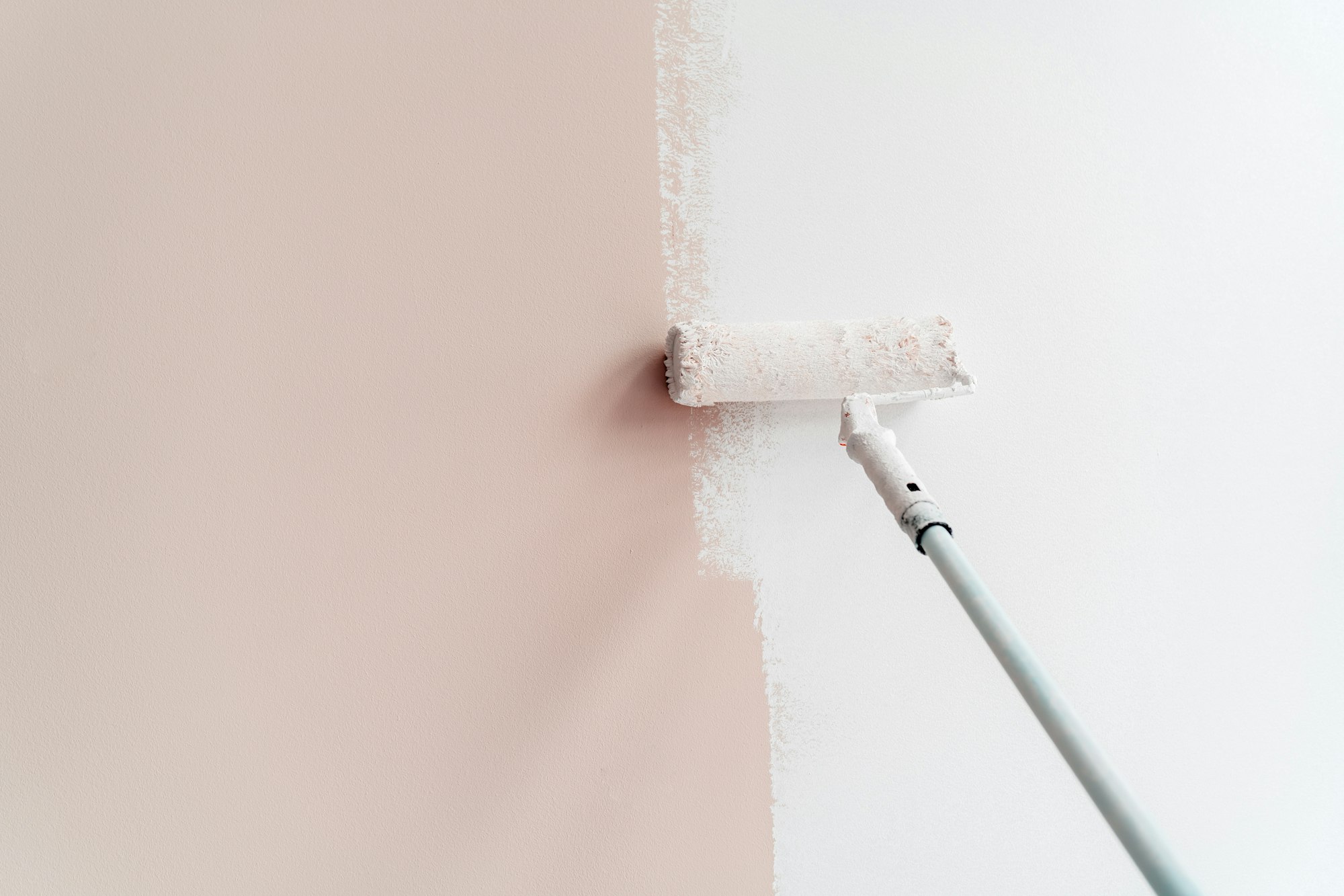 Painting house interior wall with roller into white. Apartment renovation, redecoration and repair