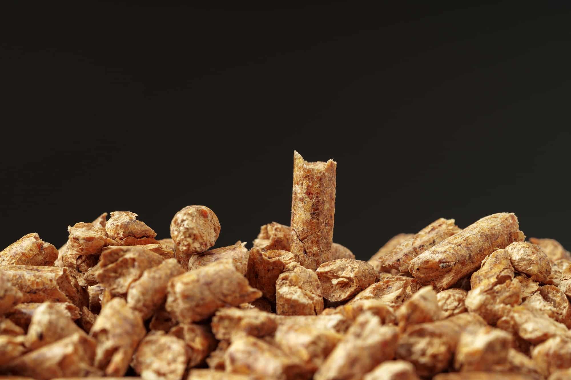 Heap of wood pellets biofuel on black background